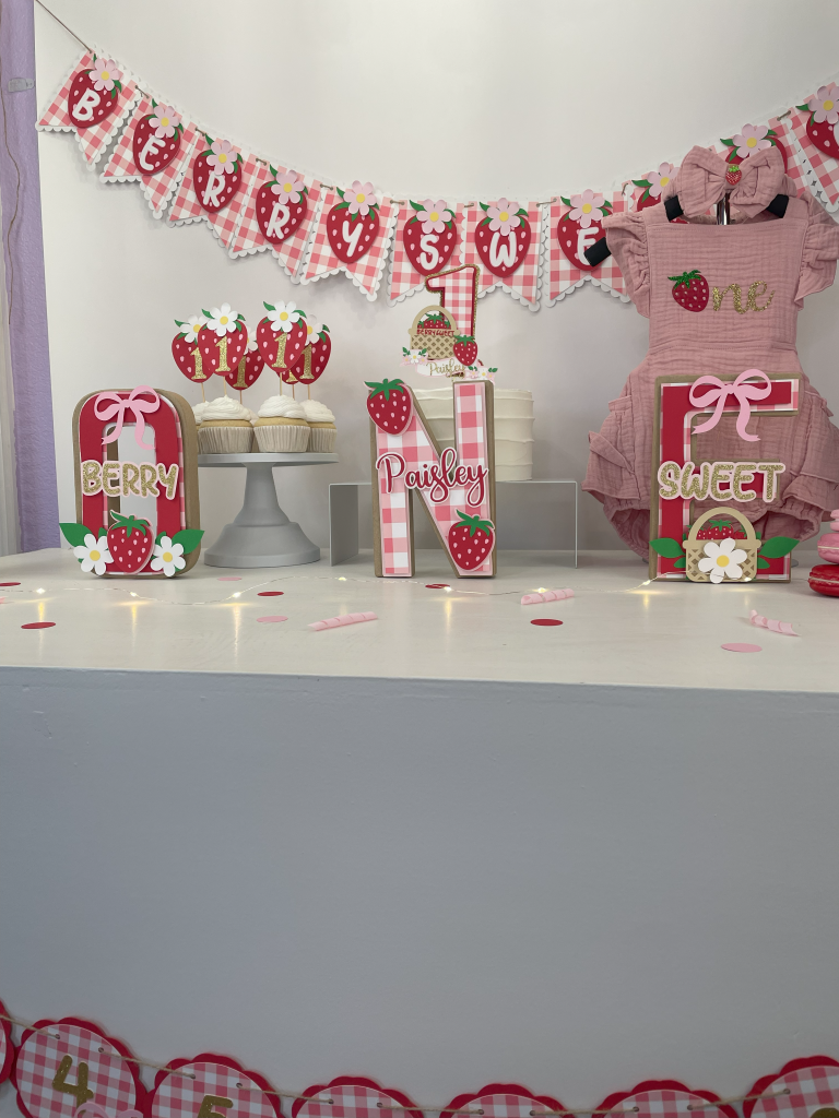 berry first birthday party decorations with banner, cake toppers, and centerpiece