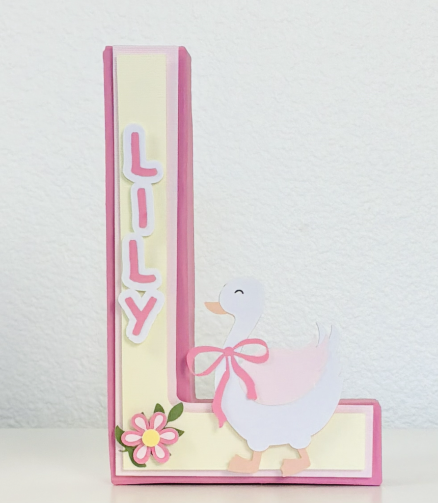 Personalized Silly Goose first birthday initial centerpiece featuring a pink and cream layered letter with a goose wearing a bow and floral accents, perfect for a baby girl’s first birthday table decor.