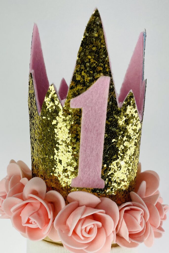 Close up image of crown, First birthday personalized princess pink tutu with white shirt, pink one, and first name and gold crown